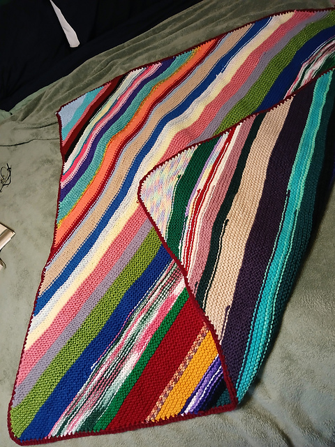 Knitted garter-stitch blanket in diagonal stripes of many scrap yarn colors